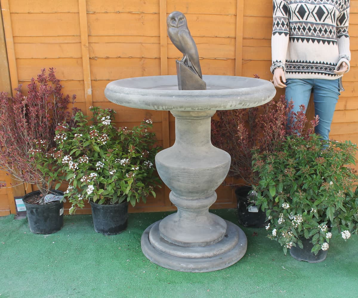 Large classic pedestal stone bird bath in a garden